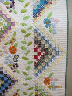 a close up of a quilt on a table top with flowers and leaves in the center