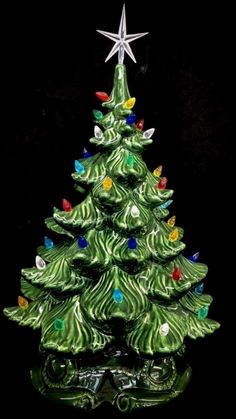 a green ceramic christmas tree with lights on it's base and a star above the top