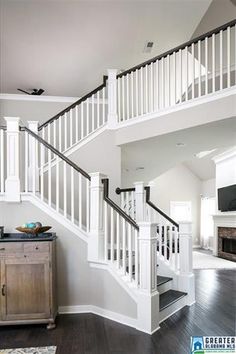 a living room with white walls and wooden flooring next to a stair case in front of a fireplace