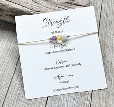 Strength Bracelet, Gemstone Strength Bracelet, Strength Gift, Crystal Bracelet, Spiritual Gift, Crystal Jewelry Genuine Amethyst, Citrine and Aquamarine gemstone beads strung on nylon cord. Dainty and simple design. Each bracelet is handmade in my studio in Florida. The bracelet comes with a keepsake card made from high quality white card. It's the perfect size for a greetings card. These bracelets make the perfect gifts and party favors for any event. If you would like any changes making to any of my items, please drop me a convo before purchasing. As all gemstones are unique and may come with slightly different shades and colors, i can't promise all beads are all the same. Check out my other items for more inspiration: https://www.arieandco.etsy.com © Arie & Co. All Rights Reserved Strength Bracelet, Spiritual Bracelets, Dance Teacher Gifts, Dancer Gift, Good Luck Bracelet, Red String Bracelet, Dance Gifts, Employee Appreciation Gifts, Friend Bracelets