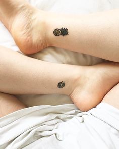 two people with pineapple tattoos on their legs laying in bed next to each other