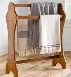 a towel rack with two towels hanging from it's sides on a wooden floor