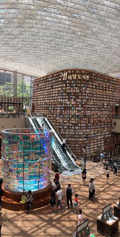 people are walking around in an open area with bookshelves on the walls and stairs