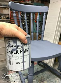 a person holding a paint can in front of a chair with the word chalk painted on it