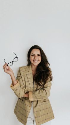 a woman holding up a pair of glasses in front of her face and smiling at the camera