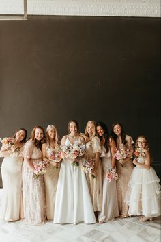 a group of women standing next to each other wearing dresses and holding bouquets in their hands