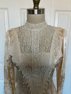 Brand: Jessica McClintock Era: 1980s Color: Ivory Material: Satin and Lace Size: 4  B 15.5  W 14" Dropped waist is 17" Condition: Excellent vintage condition, with no noticeable flaws or wear. Features: The dress features a sophisticated high neckline adorned with delicate lace, adding an air of grace and elegance. The bodice is beautifully crafted with intricate lace detailing, showcasing the impeccable craftsmanship of Jessica McClintock designs. The long sleeves are made from luxurious fabric, complemented with lace cuffs, enhancing the overall vintage charm. The dress has a series of buttons running down the back, adding a touch of vintage sophistication and ensuring a secure fit. The skirt flows gracefully from the waist to dropped waist, featuring a delicate floral pattern that adds Fitted Beige Victorian Wedding Dress, Beige Fitted Victorian Wedding Dress, Beige Long Sleeve Fitted Gown, Beige Fitted Long Sleeve Gown, Elegant Fitted Cream Victorian Dress, Victorian Cream Dress For Party, Fitted Cream Victorian Dress With Long Sleeves, Fitted Cream Vintage Dress For Party, White Victorian Dress For Party