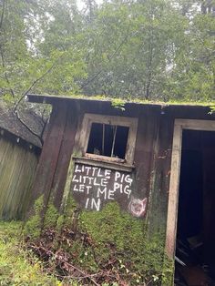 an old outhouse in the woods with graffiti written on it's windows and door