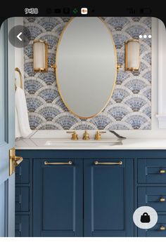 a bathroom vanity with blue cabinets and gold faucets on the mirror above it