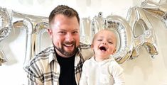 a man holding a baby in front of balloons