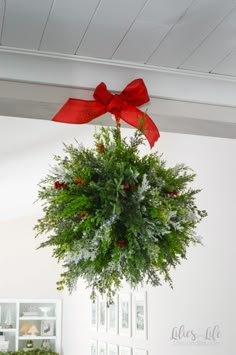 a christmas wreath hanging from the ceiling with a red bow on it's top