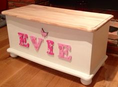 a white chest with pink letters and a butterfly on the top that says live in front of a brick wall