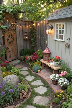 a small garden with flowers, plants and a bench in front of a house that has lights on the side of it