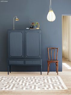 a room with a chair, cabinet and rug on the floor in front of it