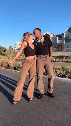 two people standing in the middle of an empty street with houses in the back ground