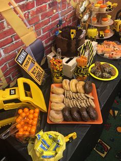 a table topped with lots of donuts and other desserts next to a brick wall