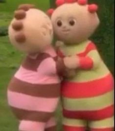 two stuffed animals are standing next to each other in front of some grass and bushes