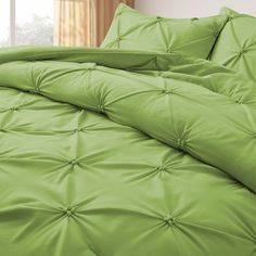 a bed with green sheets and pillows in a room