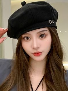 a girl with long hair wearing a black beret and holding her hand up to her ear