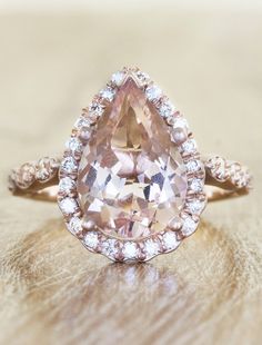 an engagement ring with a pear shaped morganite surrounded by diamonds