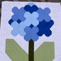 a blue and green flower on a white quilt