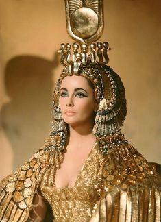 a close up of a woman wearing a gold dress and headpiece with jewels on it