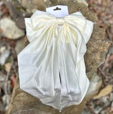 This cream-colored long bow is adorned with a charming ribbon clip that is sure to add the perfect touch of cuteness to any outfit. Elegant Cream Bow For Parties, Elegant Cream Bow For Party, Elegant Cream Bow With Ribbon Detail, Elegant Cream Bow With Ribbon, Cream Satin Bow For Wedding, Cream Ribbon Wedding Bow, Elegant Cream Satin Bow, Chic White Bow For Party, White Ribbon Bow For Gift