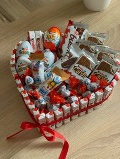 a heart shaped basket filled with candy and candies on top of a wooden table