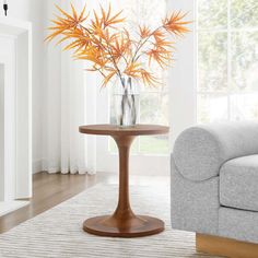 a living room scene with focus on the table and chair, which has a vase with flowers in it