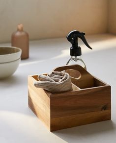 a wooden box with a bottle and soap in it sitting on a table next to a bowl