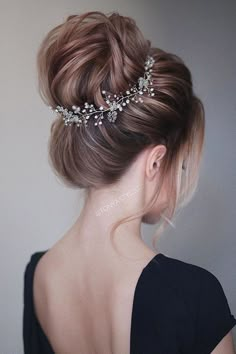 a woman wearing a hair comb with flowers on it's head and her back to the camera