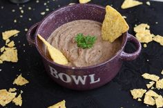 a purple bowl filled with guacamole and chips on top of a table