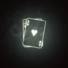 two playing cards in the dark with white hearts on each card and one heart at the top