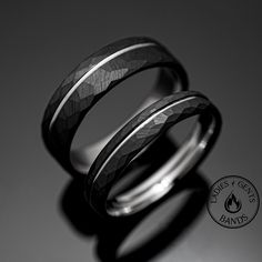 two wedding rings sitting next to each other on top of a black surface with a white background