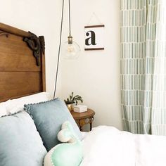 a bed with blue pillows and a wooden headboard next to a green curtained window