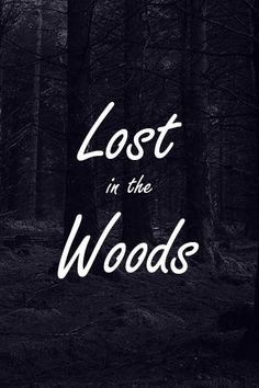 the words lost in the woods are written on black and white photo with trees behind it