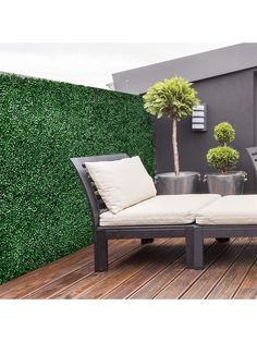 an outdoor lounge area with potted plants on the side and wooden flooring next to it