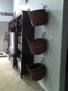 three baskets are hanging on the wall next to a tv