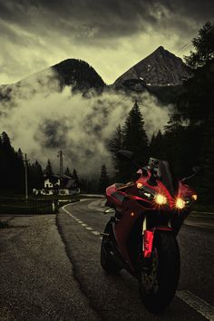 a red motorcycle is parked on the side of the road in front of some mountains