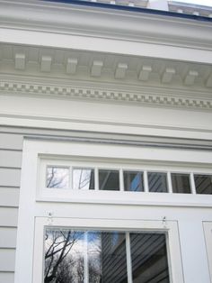 an open window on the side of a house with white siding and trimmings