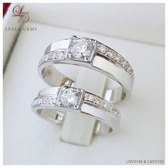 two white gold wedding rings with diamonds on top and bottom, sitting next to each other