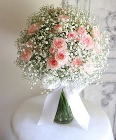 a bouquet of pink flowers sitting on top of a white table next to a wall