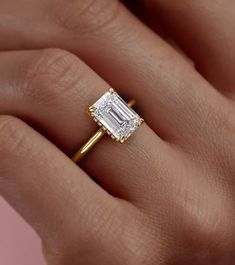 a woman's hand holding an engagement ring with a diamond in the center and side