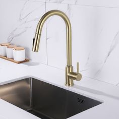 a kitchen sink with gold faucet and soap dispenser next to it