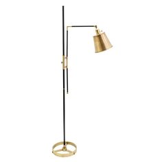 a floor lamp with a gold shade on the top and a black base, in front of a white background