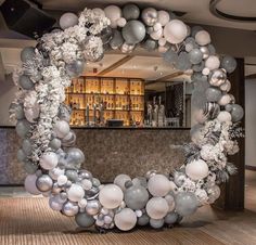 a bar decorated with silver and white balloons in the shape of a circle, surrounded by confetti