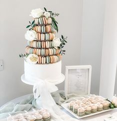 a wedding cake made out of macaroons and flowers sits on a table next to a box of cookies