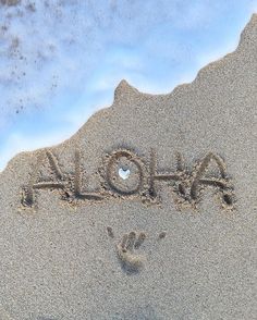 the word aloha written in the sand with a hand and footprints drawn on it