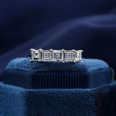 a three stone diamond ring sitting on top of a blue velvet covered cushioned surface