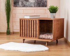 a wooden cabinet sitting on top of a hard wood floor next to a potted plant